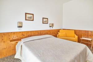 Un dormitorio con una cama y una silla amarilla. en Albergo Natalina, en Finale Ligure