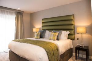 a bedroom with a large bed with a green headboard at Roundthorn Country House & Luxury Apartments in Penrith