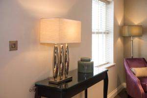 a living room with a lamp and a table at Roundthorn Country House & Luxury Apartments in Penrith