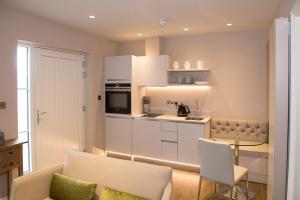a living room with a couch and a kitchen at Roundthorn Country House & Luxury Apartments in Penrith