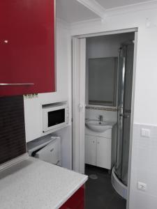 een kleine badkamer met een wastafel en een magnetron bij Nazaré - The Little Star in Nazaré