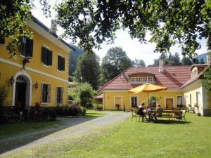 a group of people sitting under an umbrella in front of a house at Lindenhof in Murau