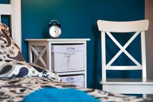a bedroom with blue walls and a bed and a chair at FatCat Apartments in Krakow
