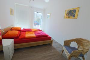 リューネブルクにあるCity Apartment - Lüneburg Am Schierbrunnenのベッドルーム1室(カラフルなシーツと椅子付きのベッド1台付)