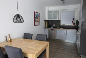 cocina y comedor con mesa de madera y sillas en City Apartment - Lüneburg Am Schierbrunnen, en Lüneburg