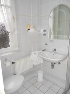 uma casa de banho branca com um lavatório e um WC em Hotel Heuberg em Norderstedt