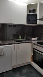 a kitchen with white cabinets and a microwave at Somerset House Apartments in Blackpool