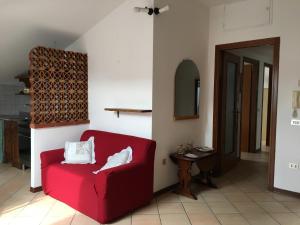 - une chaise rouge dans le salon avec un miroir dans l'établissement Villa Vittoria, à Marina di Pietrasanta