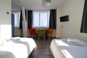 a hotel room with two beds and a table and chairs at Hotel Saint Vincent in Poeldijk