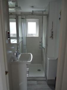 a white bathroom with a sink and a shower at Gwyndaf Holiday Cottage in Llangoed +27 photos