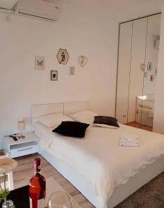 a white bed in a bedroom with a bottle of wine at Studio Confort 3 in Bucharest