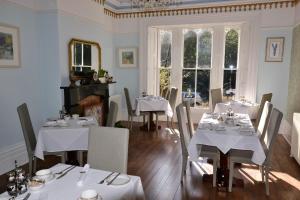 a dining room with white tables and chairs and windows at Glendon Bed and Breakfast in Matlock