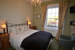 a bedroom with a bed and a window and a chair at Glendon Bed and Breakfast in Matlock