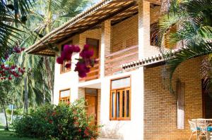 a brick house with purple flowers in front of it at Refúgios Parajuru - Villa Cristiano in Parajuru