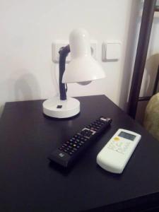 a lamp and a remote control sitting on a table at Comfortable inexpensive apartmets near metro in Athens