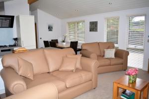 uma sala de estar com dois sofás castanhos e uma mesa em Ein Yfory em Benllech
