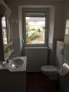 uma casa de banho com um lavatório, um WC e uma janela. em 4-Sterne Ferienhaus Achat-Alm mit E-Ladestation em Vollmersbach