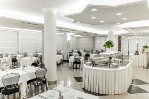 una sala da pranzo con tavoli e sedie bianchi di Hotel Imperial a San Benedetto del Tronto