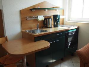 a small kitchen with a sink and a table at Apartmenthaus Aurum in Ahlbeck