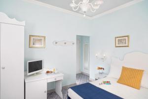 een slaapkamer met een bed en een bureau met een televisie bij Hotel Villa Nefele in Giardini Naxos