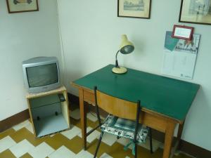 a desk with a television and a lamp and a chair at Pensione Rinascente in Pisa