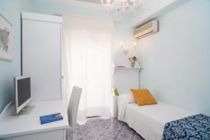 a bedroom with a bed and a desk with a tv at Hotel Villa Nefele in Giardini Naxos