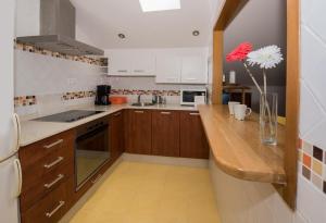 a kitchen with wooden cabinets and a vase with a red flower at Apartamentos LLANES & GOLF in Llanes