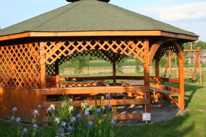 a wooden gazebo with benches in a field at Domki i pokoje przy ujściu in Solina