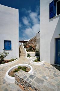a white house with blue windows and a staircase at Amorgion Village in Katapola