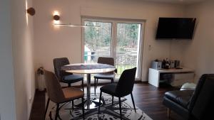 ein Wohnzimmer mit einem Tisch, Stühlen und einem Fenster in der Unterkunft tolles komfortables Appartement Zaubersee in Bergisch Gladbach