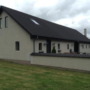 ein weißes Haus mit einem schwarzen Dach und einem Hof in der Unterkunft Bøllingsø Feriehus in Silkeborg