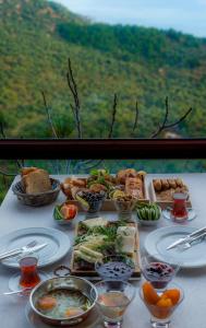 einen Tisch mit Teller mit Lebensmitteln und Schüsseln mit Lebensmitteln in der Unterkunft Assos Kartal Yuvasi Hotel in Sazlı
