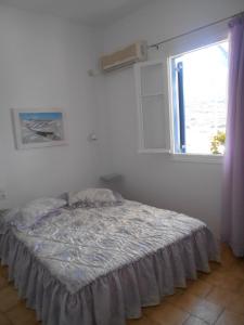 a bed in a room with a window at Angeliki Pension in Katapola