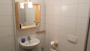 ein weißes Badezimmer mit einem Waschbecken und einem Spiegel in der Unterkunft PEMATRA Ferienwohnung Fährblick in Travemünde
