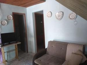 ein Wohnzimmer mit einem Sofa und einem TV in der Unterkunft Casa do Cantinho in Imbituba