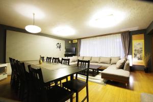 a dining room and living room with a table and a couch at AKKO's Guest House in Sapporo