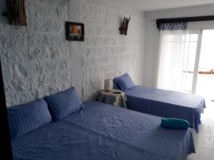 1 dormitorio con 2 camas con sábanas azules y ventana en Posada Ocean View, en Providencia