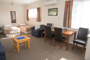sala de estar con mesa, sillas y sofá en Greymouth Motel, en Greymouth