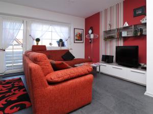 グレートジールにあるFerienwohnung Sonnenkieker Greetsielのリビングルーム(オレンジ色のソファ、テレビ付)