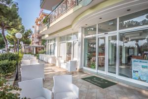 przednia część sklepu z białymi krzesłami i oknami w obiekcie Ciccio Hotel w mieście Misano Adriatico