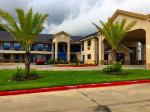 a large building with palm trees in front of it at Americas Best Value Inn & Suites Mont Belvieu Houston in Eldon