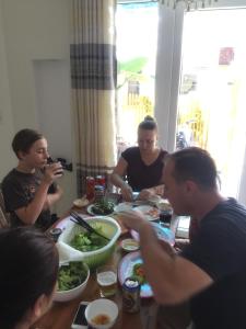 a group of people sitting around a table eating food at Hoi An beach house in Hoi An
