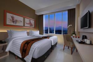 a hotel room with two beds and a desk and a window at ASTON Banyuwangi Hotel and Conference Center in Banyuwangi