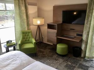 Schlafzimmer mit einem Bett, einem TV und einem Stuhl in der Unterkunft Landhotel Witte-König in Garrel