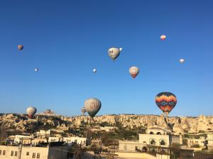 eine Gruppe von Heißluftballons, die über eine Stadt fliegen in der Unterkunft Kemal's Guest House in Goreme