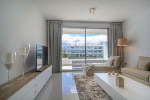 een woonkamer met een bank en een groot raam bij Belaire 4 bedroom apartment in Estepona