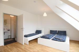 two beds in a white room with a bathroom at Central Living Apartments - Reumannplatz in Vienna