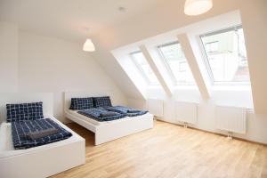 two beds in a attic bedroom with windows at Central Living Apartments - Reumannplatz in Vienna