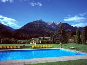 a swimming pool with chairs and mountains in the background at Waldpension Putz in Berg im Drautal