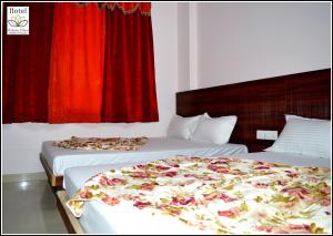 2 Betten in einem Hotelzimmer mit roten Vorhängen in der Unterkunft Hotel Thikana Palace in Jaipur